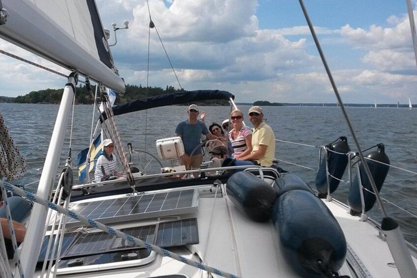Ein Segelboot mit Personen an Bord, ein Wasserweg und eine entfernte Uferlinie mit Bäumen. 3