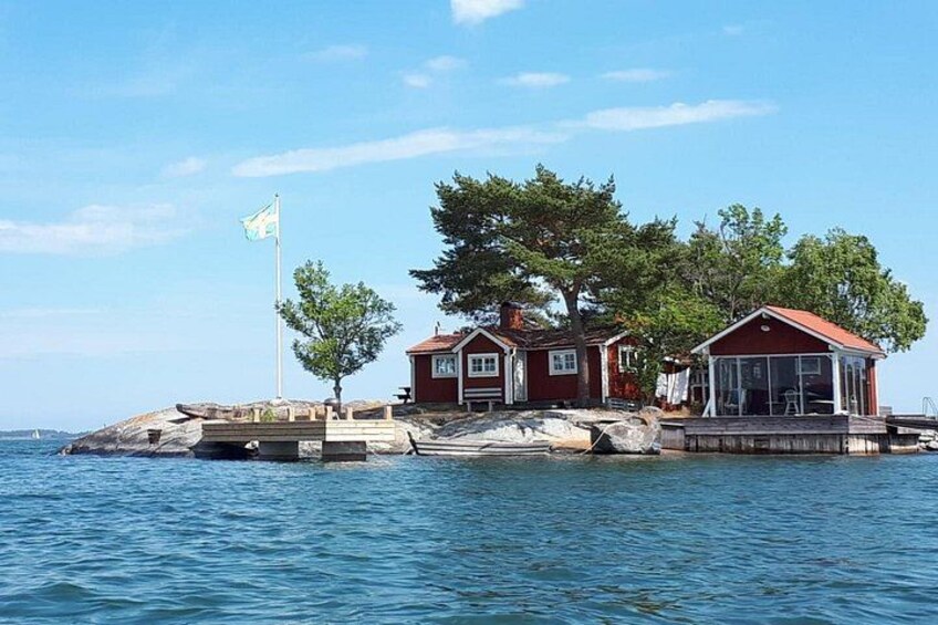 Ein Haus auf einer felsigen Insel mit einem Steg, umgeben von Wasser. 5