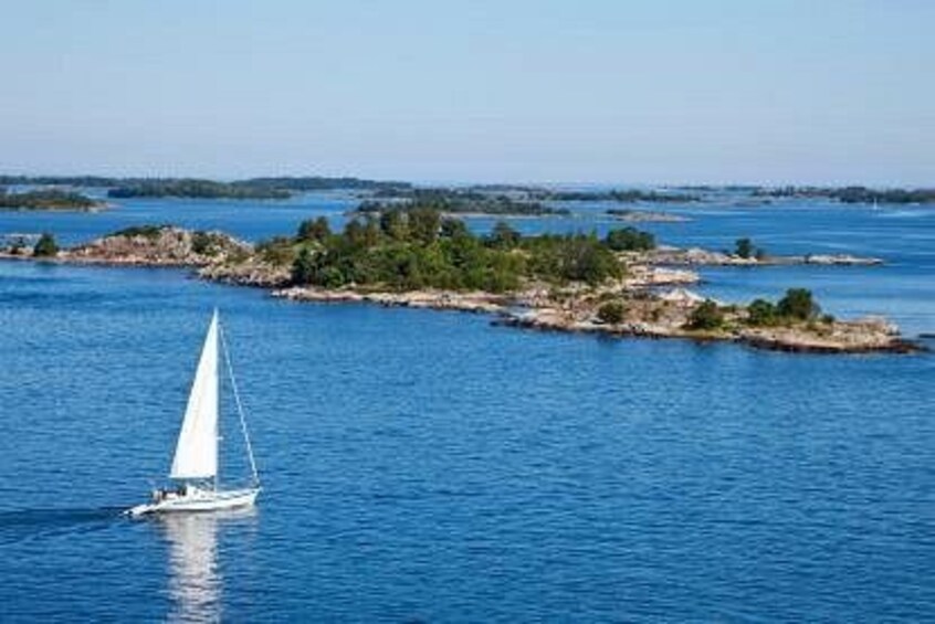 Ein Segelboot auf ruhigem Gewässer, im Hintergrund Inseln. 4