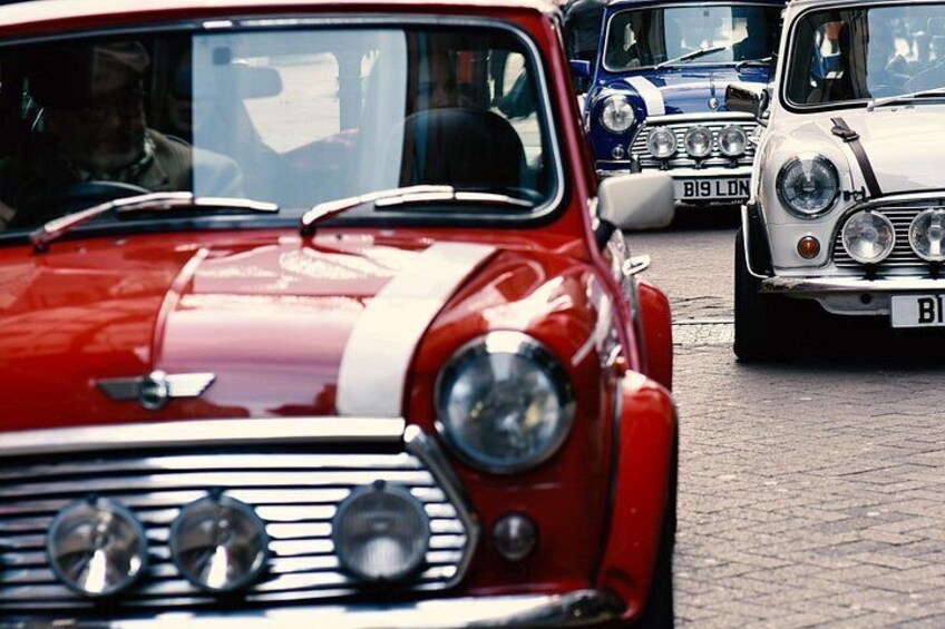Vintage cars lined up on a cobblestone street. 5