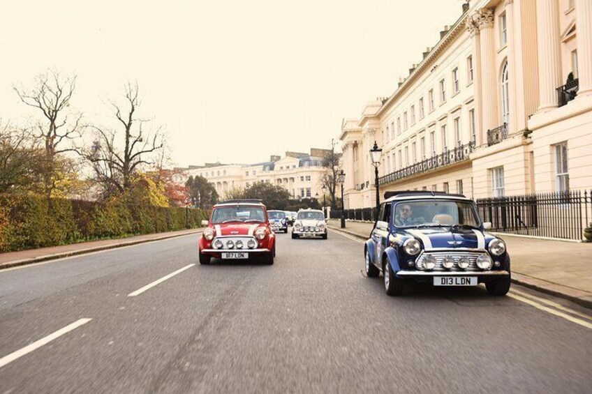 A street with classic cars driving on a road lined with historic buildings. 5
