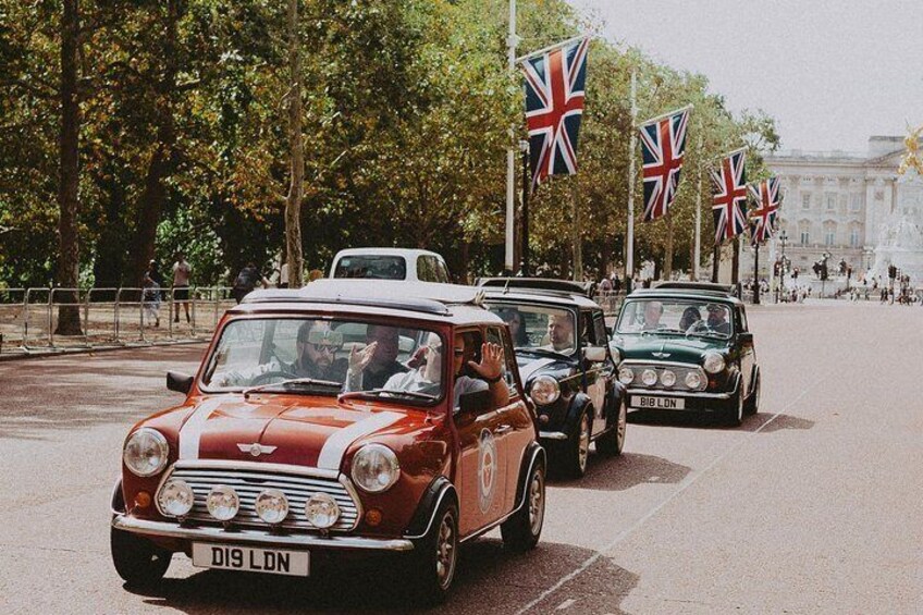 Vintage cars lined up on a street with British flags. 4
