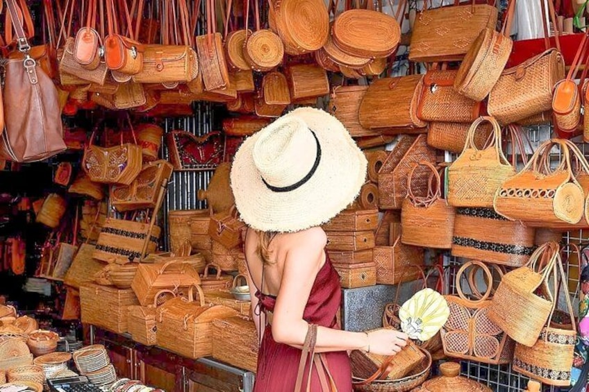 A person browsing through a variety of woven bags and baskets in a market. 3