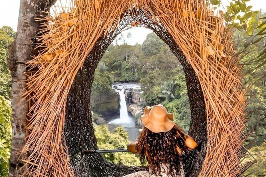 A person in a hat looking through a woven arch at a waterfall. 2