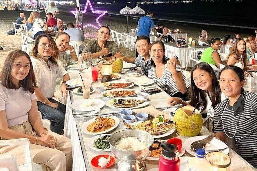 A group of people dining at an outdoor restaurant with various dishes on the table. 4