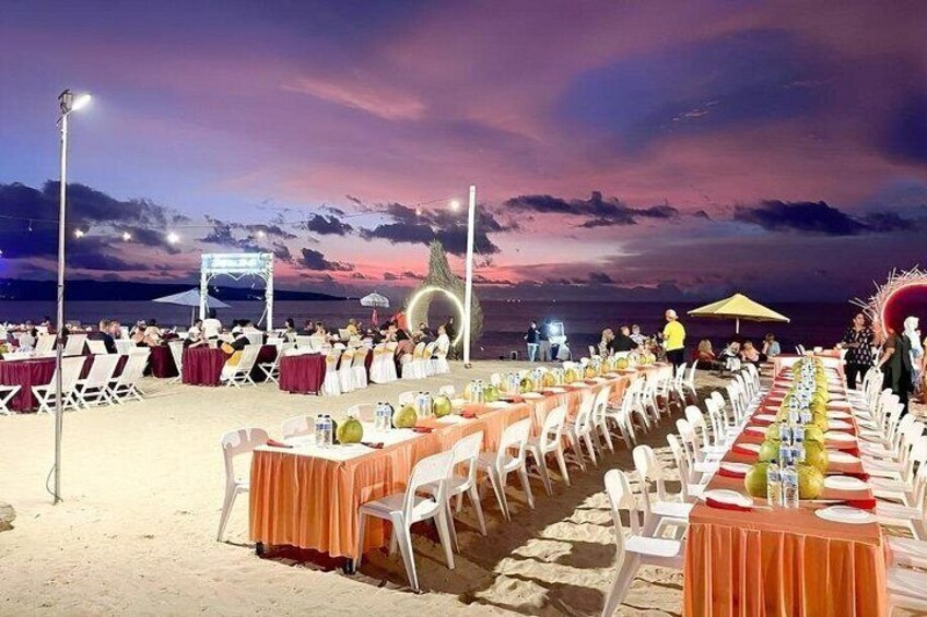 A beachside event with tables and chairs set up for an evening gathering. 5