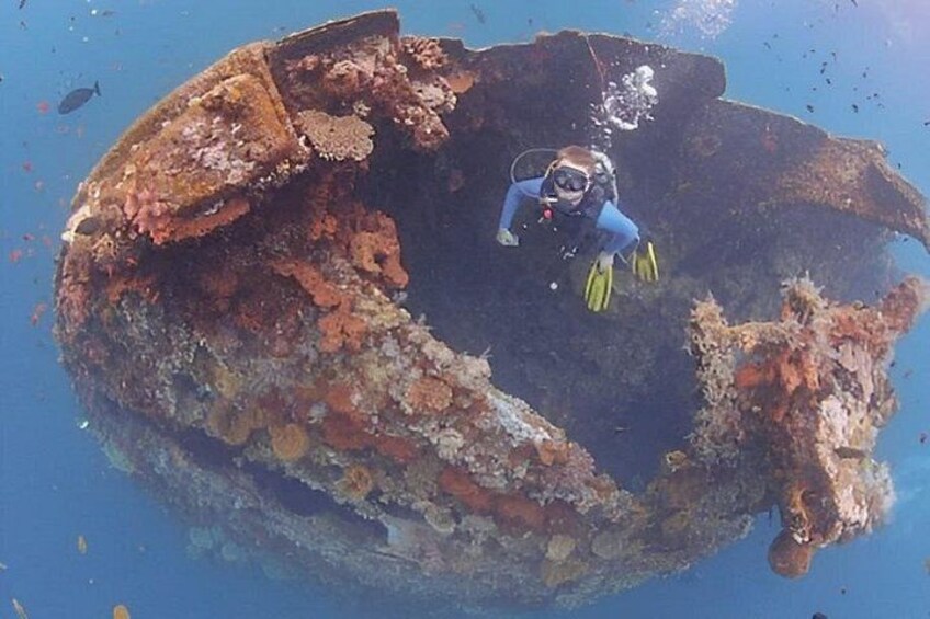 A diver exploring a large, rusted shipwreck underwater. 4