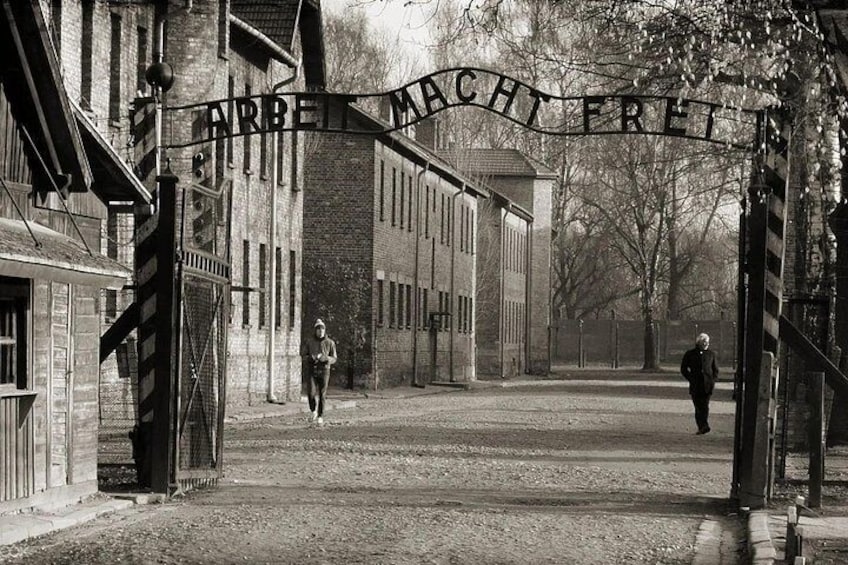 A street with a sign reading 'ARBEIT MACHT FREI' and a person walking. 1