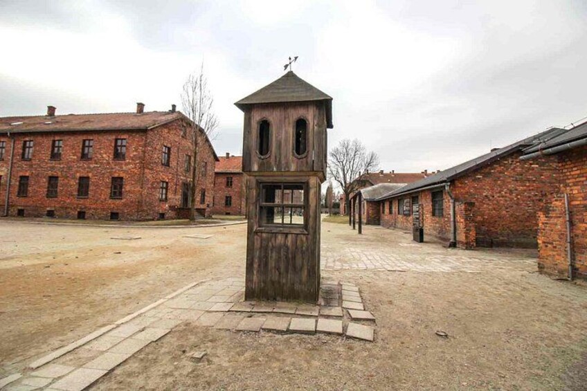 Un edificio in mattoni con una torre in legno al centro, circondato da altre strutture in laterizio. 3