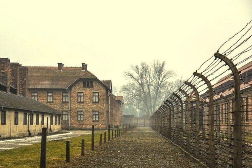 A barbed wire fence, a brick building, and leafless trees. 2