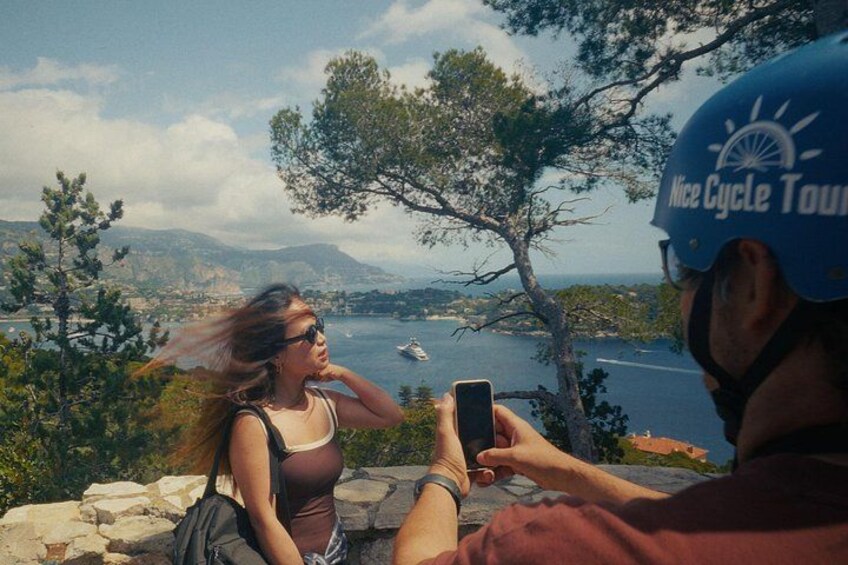 Una persona che fotografa un paesaggio costiero con alberi e un tratto d'acqua. 4