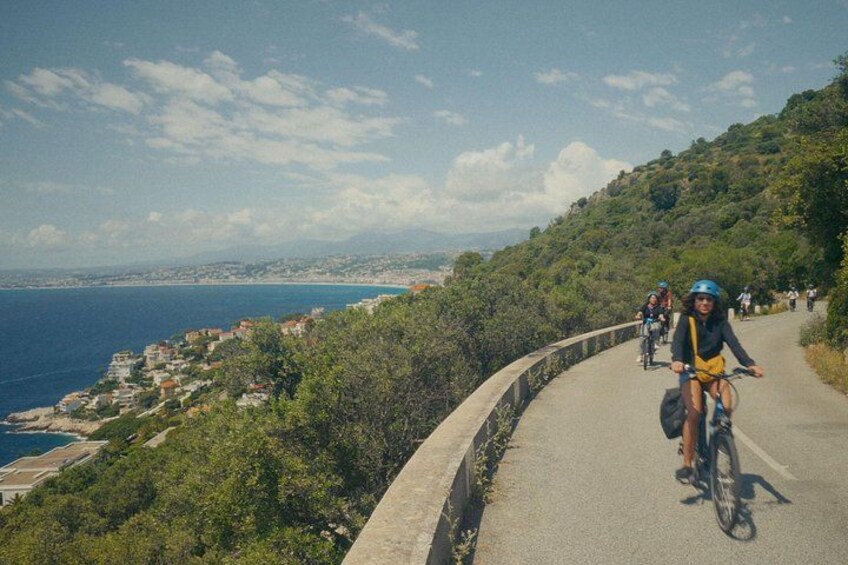 Cyclists on a coastal road with a view of the sea and a hilly landscape. 1