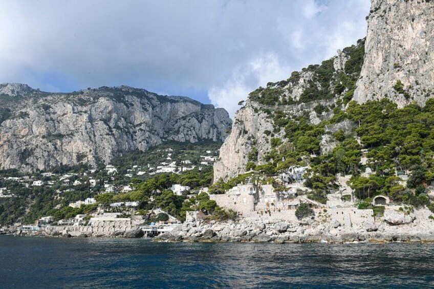 A coastal town with buildings on a cliff, rocky terrain, and a body of water. 5