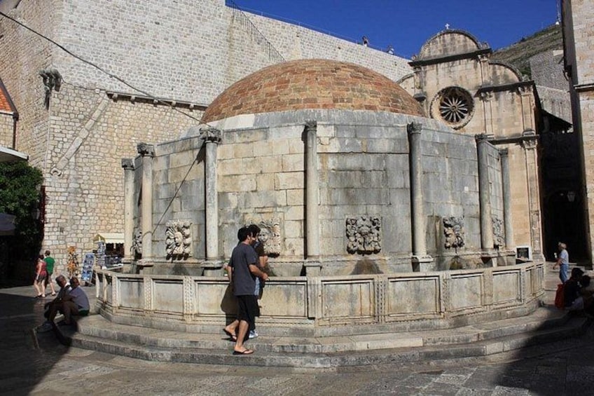 Una estructura histórica de piedra con una cúpula y columnas, rodeada por un muro de piedra y escalones. 5