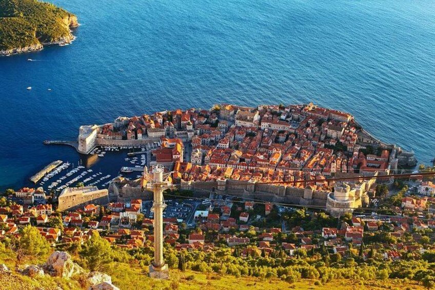 A coastal town with a fortified wall, a prominent tower, and a marina. 1