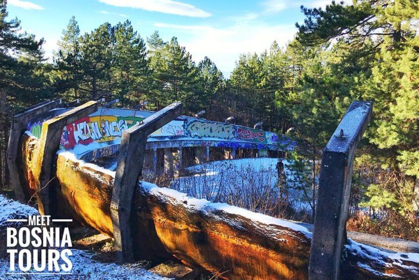 A snow-covered landscape with graffiti on a wooden structure. 2