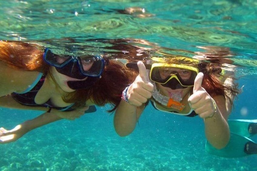 Two people underwater, wearing snorkeling gear, giving thumbs up. 1