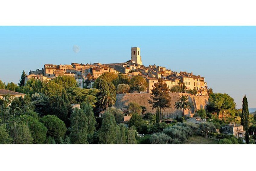 A coastal town with a prominent tower, lush greenery, and a clear sky. 2