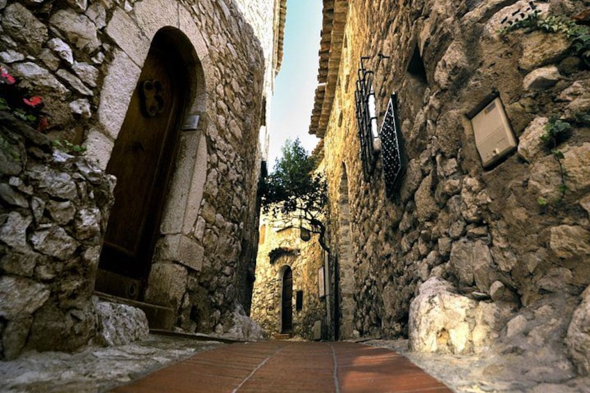 Un chemin de pierre mène à travers un ancien bâtiment en pierre, doté d’arcades et d’un sol carrelé. 3