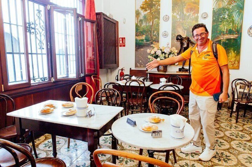 A restaurant interior with wooden furniture, a tiled floor, and a large painting on the wall. 5