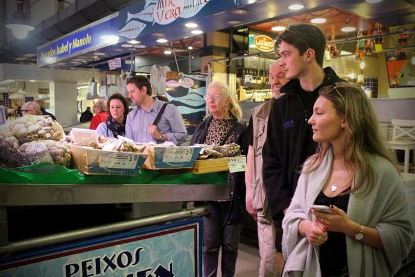 A market stall with seafood, a sign reading 'PEIXOS,' and people browsing. 3