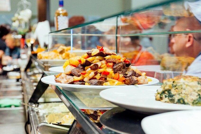 A buffet with various dishes, including a plate with a meat and vegetable mixture, and a glass display case with more food options. 5