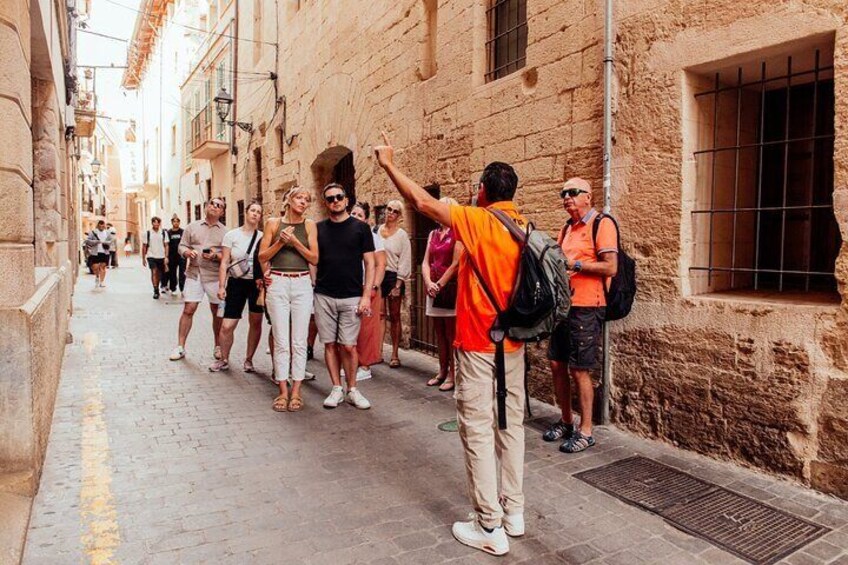 En gruppe turister går ned ad en smal gade med historiske bygninger. 4