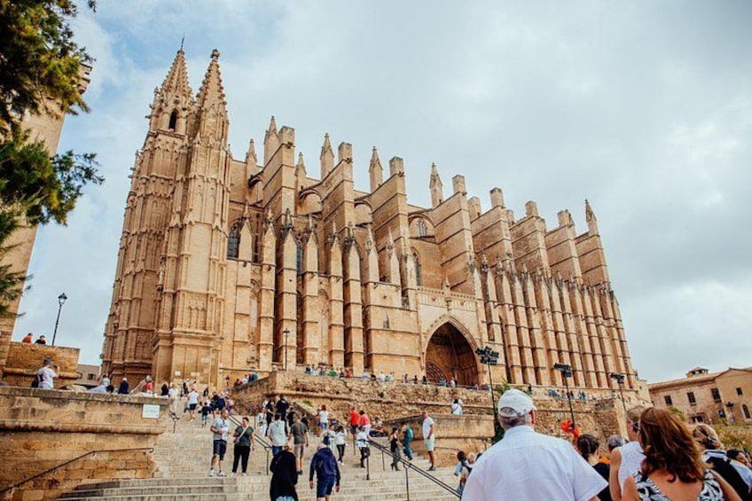 En stor katedral med gotisk arkitektur, en markant indgang og en menneskemængde, der går op ad trapperne. 1