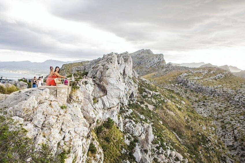 A rocky mountain landscape with a group of people standing on a ledge. 2