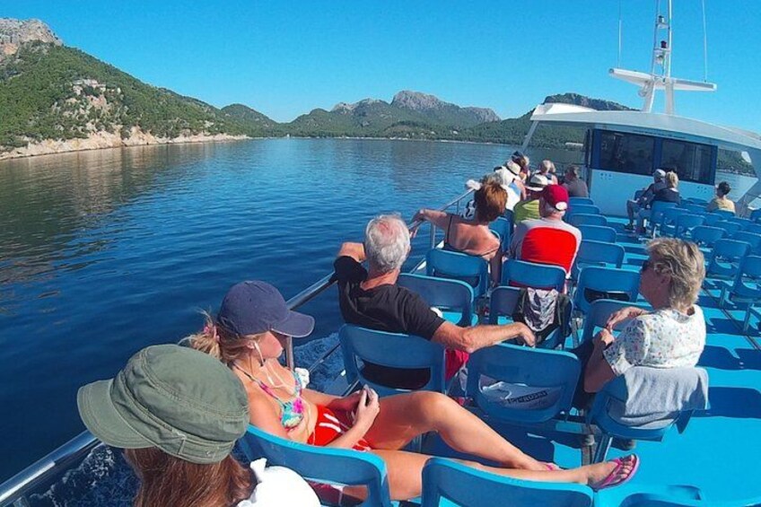 A boat with people seated, water, and distant hills. 2