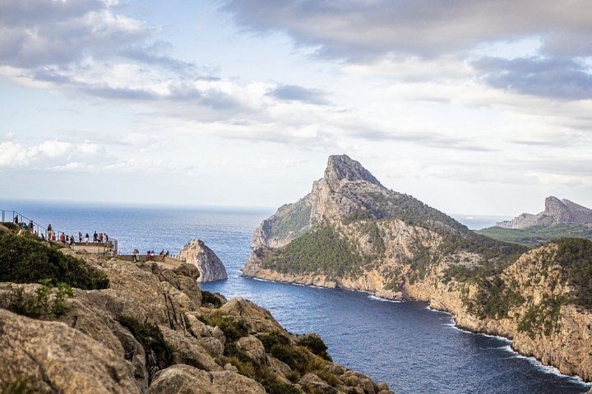 A coastal landscape with rocky cliffs, a prominent rock formation, and a sea view. 4
