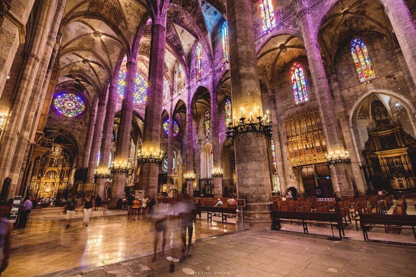 A cathedral interior with high vaulted ceilings, stained glass windows, and rows of pews. 1