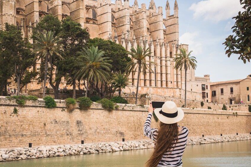A person taking a photo of a historic building with palm trees in the foreground. 3