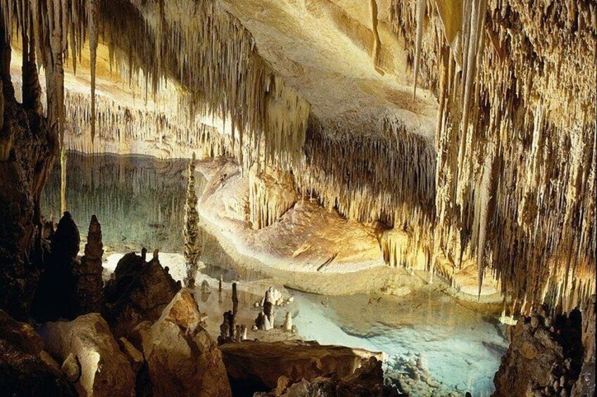 A cave with stalactites and stalagmites, a water pool, and rock formations. 4