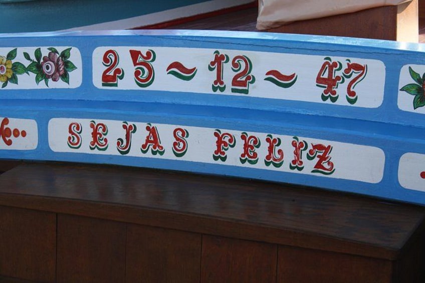 A wooden bench with a colorful sign that reads '25-12-47' and 'SEJAS FELIZ' with decorative elements. 4