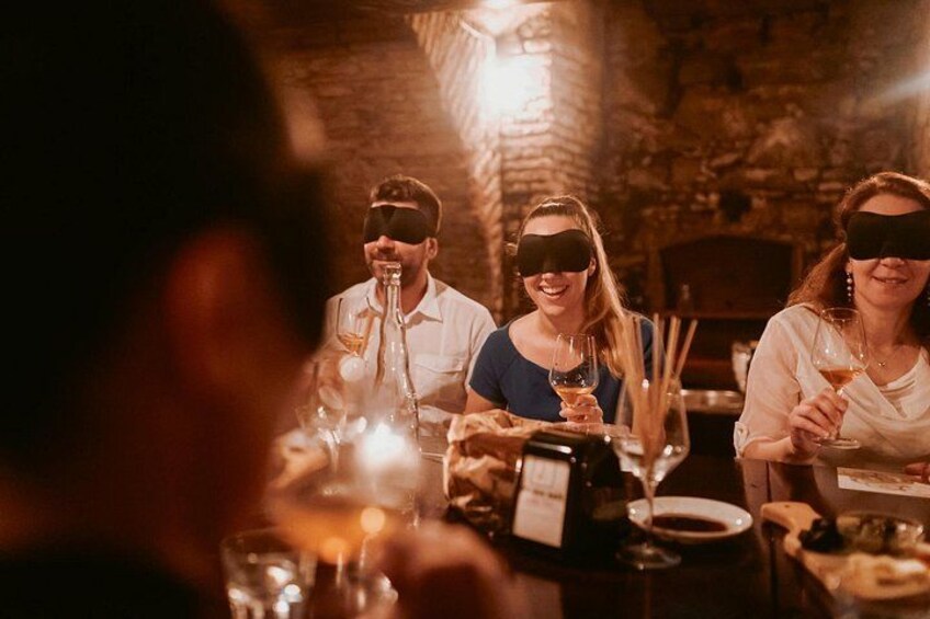 En grupp människor som äter middag på en restaurang med dämpad belysning och väggar av sten. 3