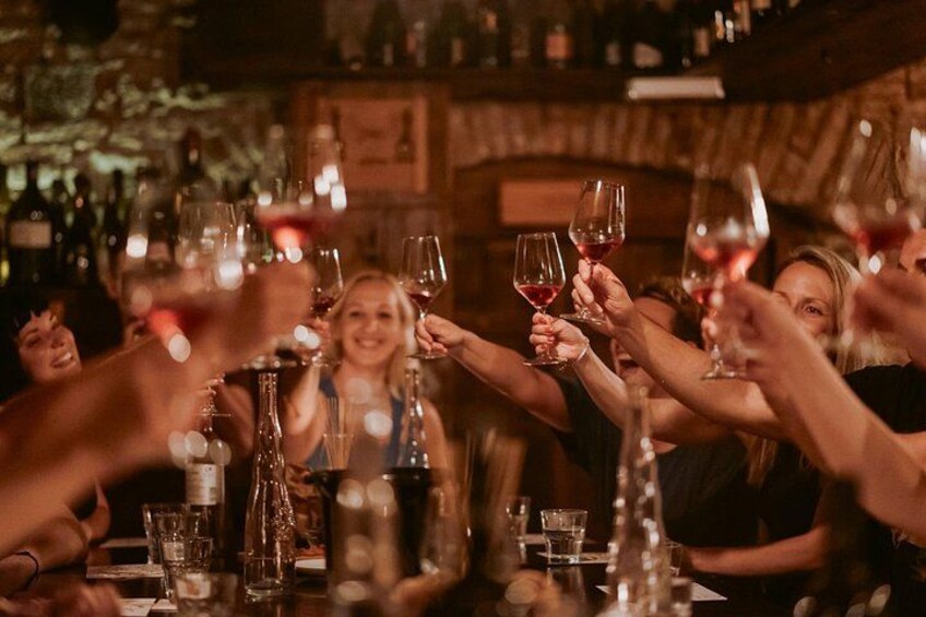 En gruppe mennesker skåler med vinglas på en bar. 2