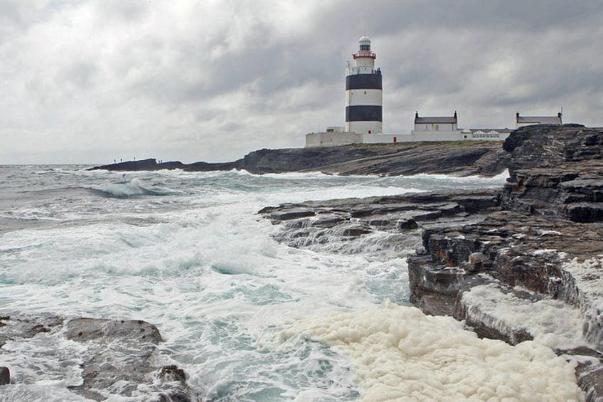 Un faro en una costa rocosa con olas marinas agitadas. 1