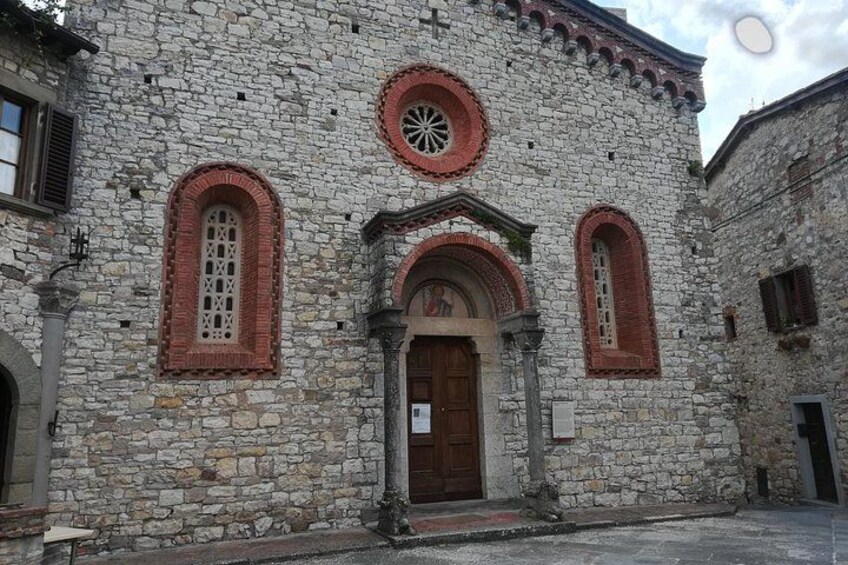 Un bâtiment en pierre doté d’une porte d’entrée en arc de cercle, flanquée de deux fenêtres en arc également, avec des encadrements rouges, et d’une fenêtre circulaire au-dessus de la porte. 2