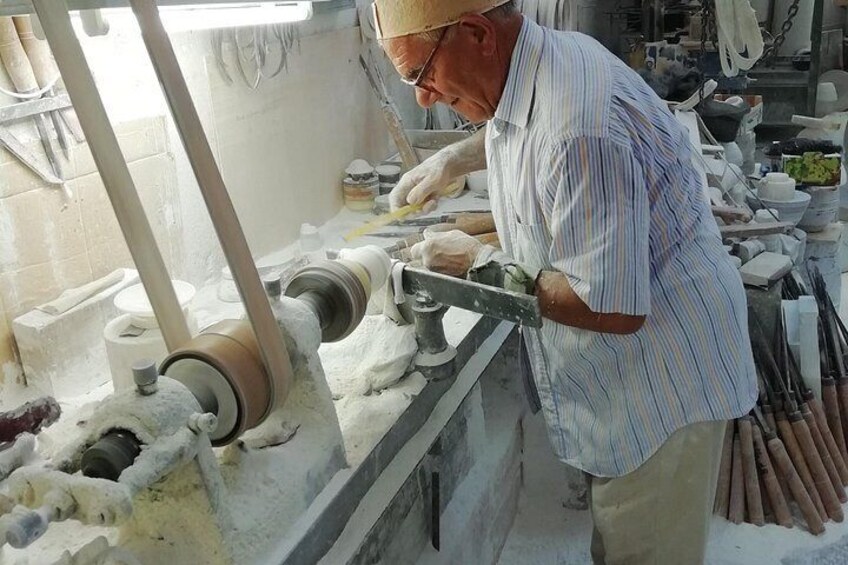 A person working with pottery on a wheel, surrounded by pottery tools and materials. 1