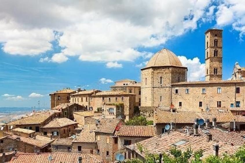 A historic town with a prominent church, a bell tower, and terracotta-roofed buildings. 4