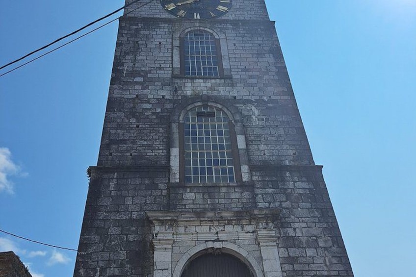 Une haute tour en pierre, dotée d’une horloge et de fenêtres en arc. 2