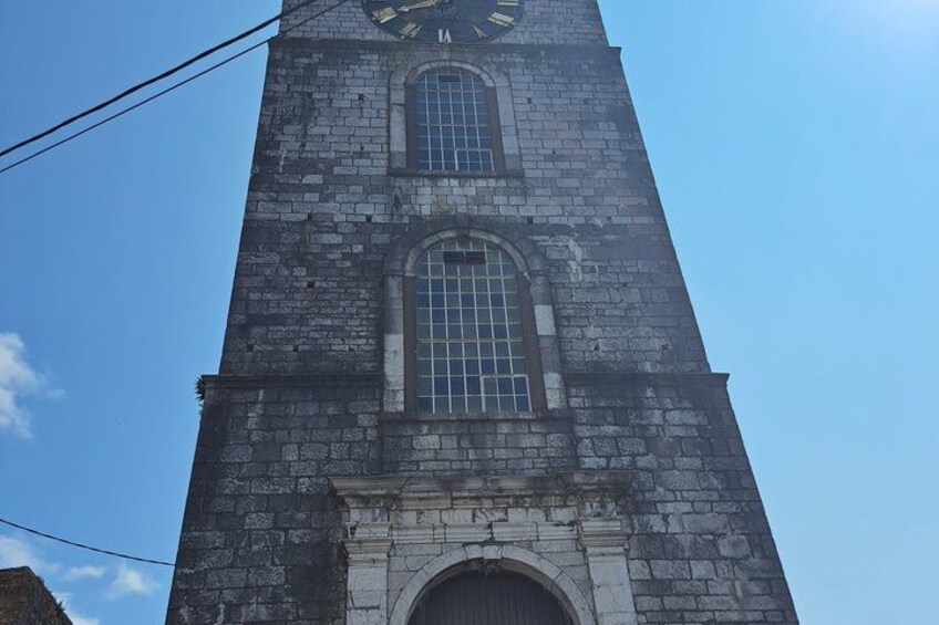 Una alta torre de piedra con una esfera horaria grande y ventanas arqueadas. 2