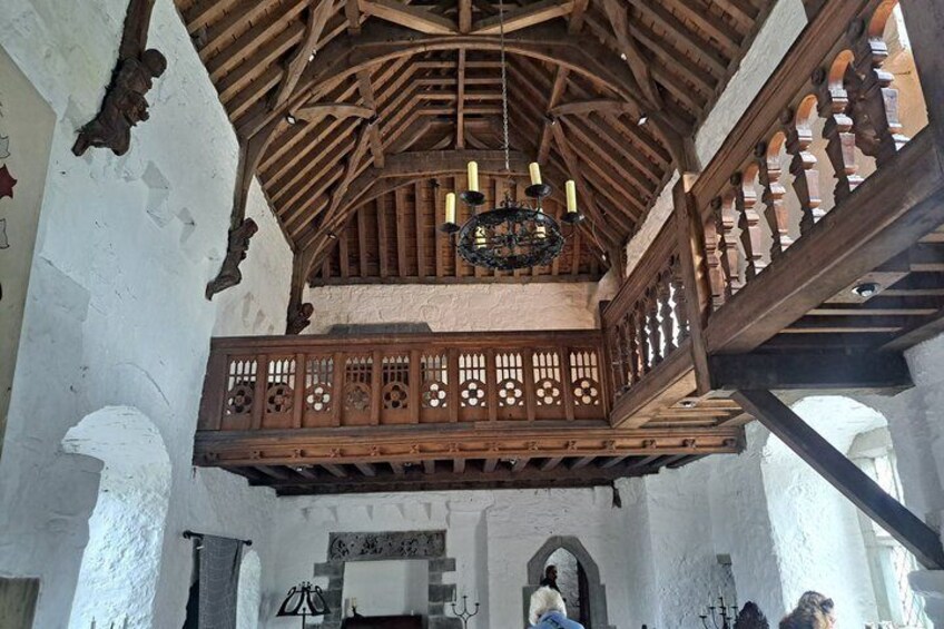 A wooden balcony with intricate lattice work, a stone wall, and a chandelier. 3