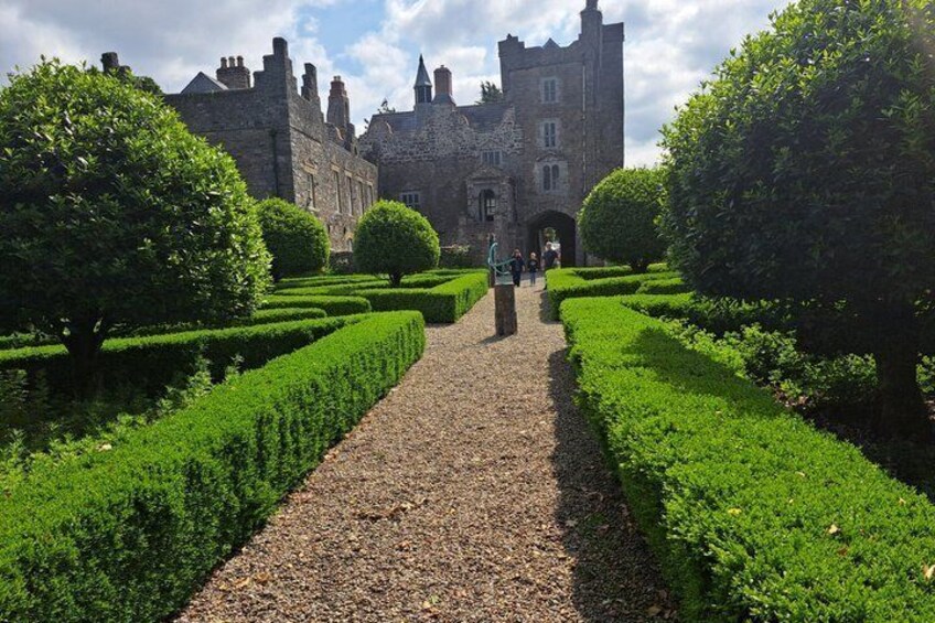 A castle with a gravel pathway leading to it, surrounded by neatly trimmed hedges. 4