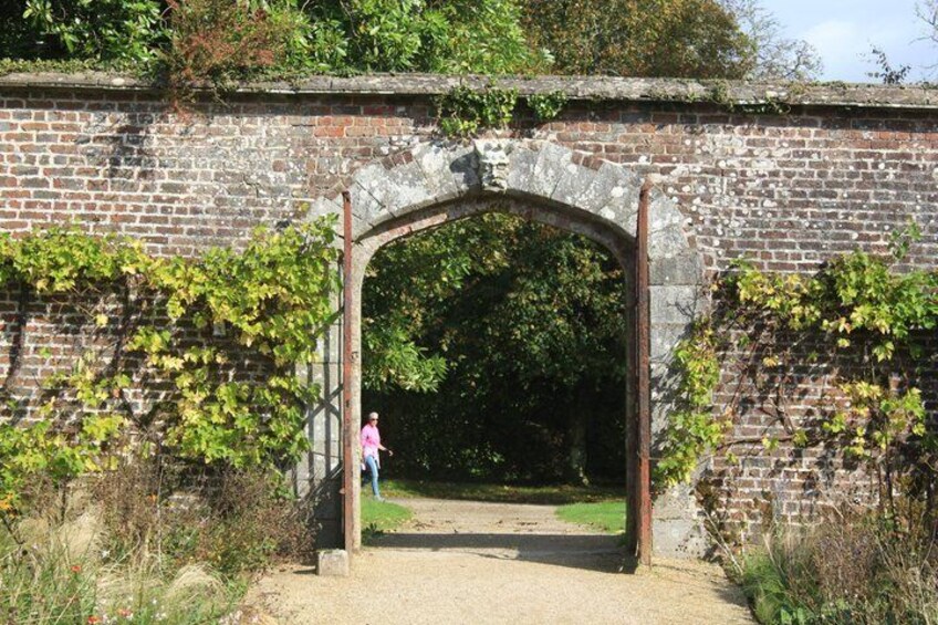 An arched brick gateway with a person walking through it. 2