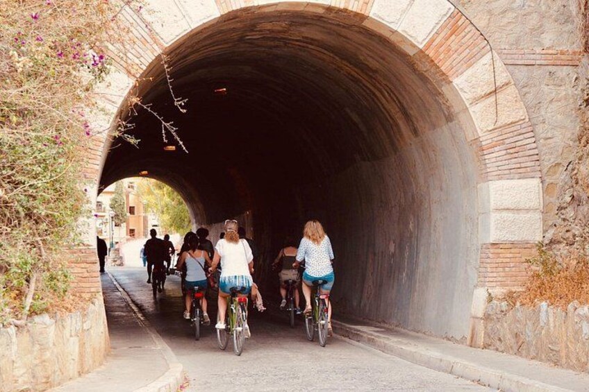A stone tunnel with cyclists riding through. 1