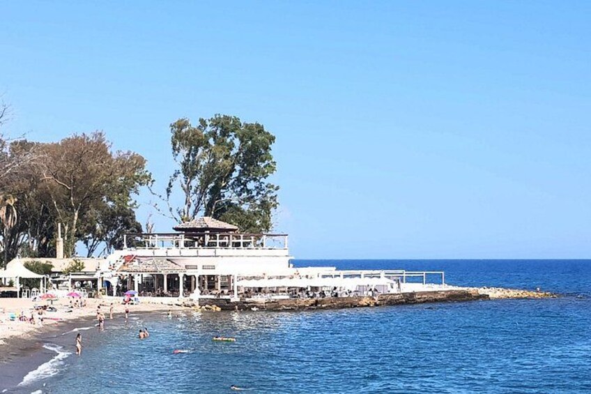A beach with a white building, trees, and the ocean. 2