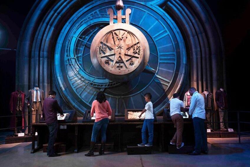 Eine große Uhr mit mehreren Zifferblättern und Zeigern, umringt von Menschen, die sie betrachten. 1