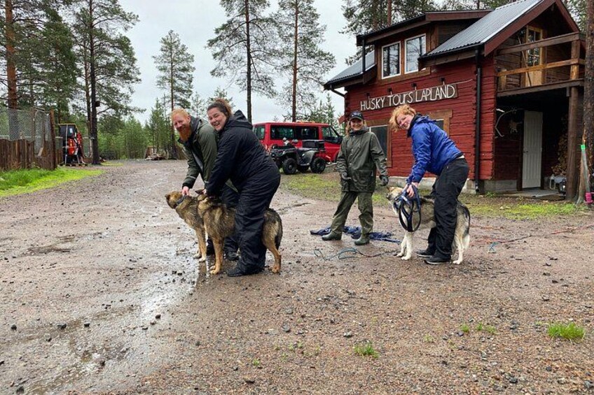 Cuatro personas interactúan con perros frente a un edificio con la inscripción 'HUSKY TOOLS LAPLAND'. 2